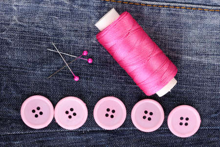 Colorful sewing buttons with thread on jeans closeupの写真素材