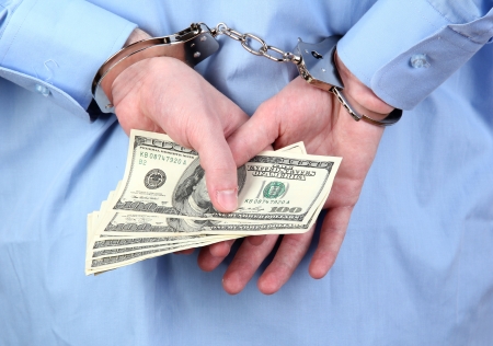 man in handcuffs is holding dollars, on black backgroundの写真素材