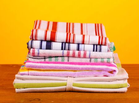 kitchen towels on wooden table on orange background close-up