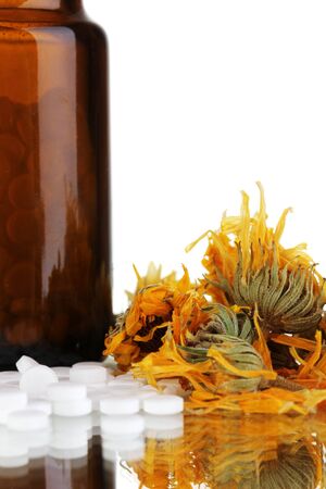 bottle with pills and herbs on white background. concept of homeopathyの写真素材