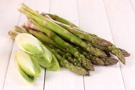 Fresh asparagus and chicory on white wooden table backgroundの写真素材