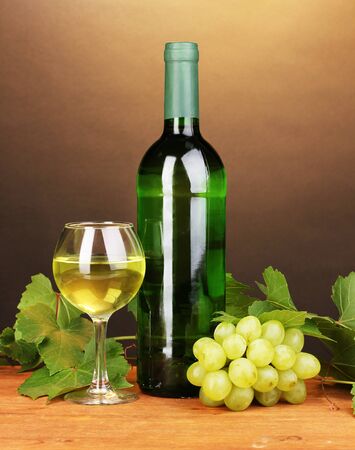 Bottle of great wine with glass on wooden table on brown background