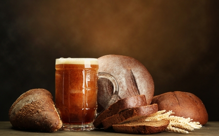 tankard of kvass and rye breads with ears, on wooden table on brown backgroundの写真素材