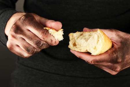 homeless man holding a white bread, close-upの写真素材