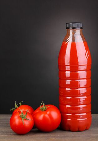 Tomato juice in bottle on wooden table on grey backgroundの写真素材