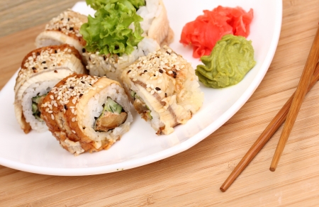 Tasty rolls served on white plate with chopsticks on wooden table close-upの写真素材