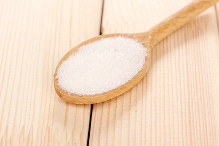 White sugar in spoon on wooden backgroundの写真素材