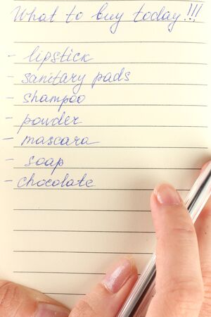 woman's hand holding a notebook with a shopping list close-upの写真素材