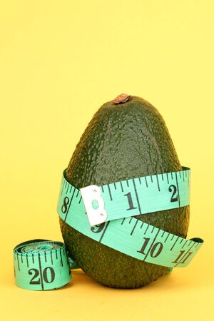 avocado with measuring tape on yellow backgroundの写真素材