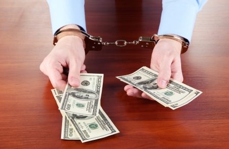 Businessman in handcuffs counts the money for bribesの写真素材