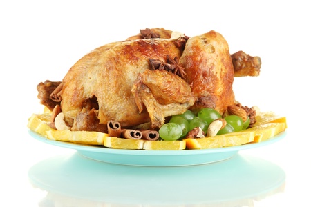 whole roasted chicken with grapes, oranges and spices on blue plate isolated on whiteの写真素材