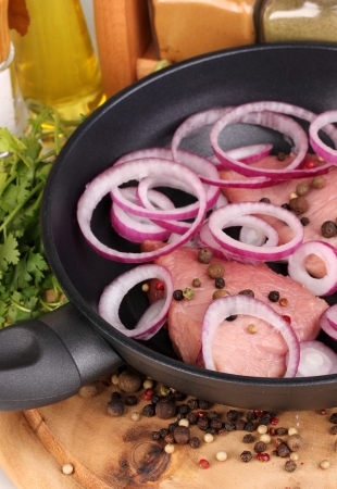A pieces of pork with onions fried in pan with herbs, spices and cooking oil on board close-upの写真素材