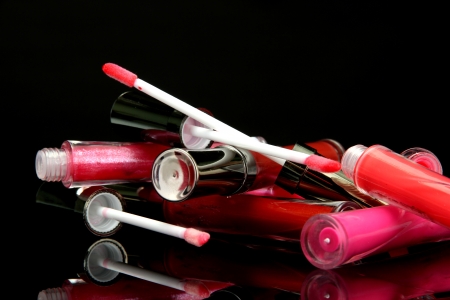 beautiful lip glosses with rose petals, on black backgroundの写真素材