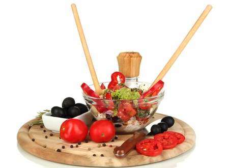 Fresh greek salad in glass bowl surrounded by ingredients for cooking isolated on whiteの写真素材