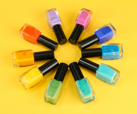 Group of bright nail polishes, on yellow background