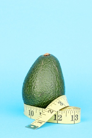 avocado with measuring tape on blue backgroundの写真素材