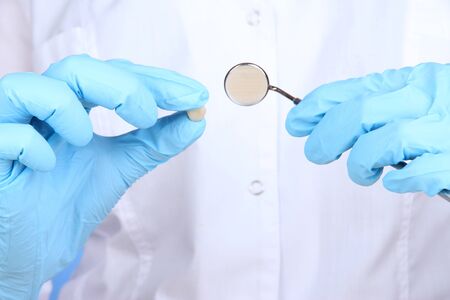 Hands in blue glove holding dental mirror on white backgroundの写真素材
