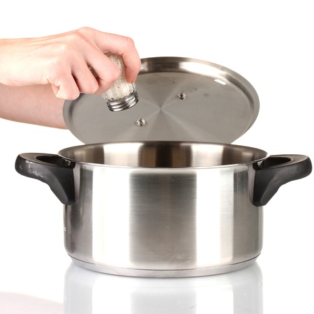 Hand adding salt using  salt shaker isolated on whiteの写真素材