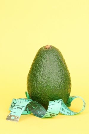 avocado with measuring tape on yellow backgroundの写真素材