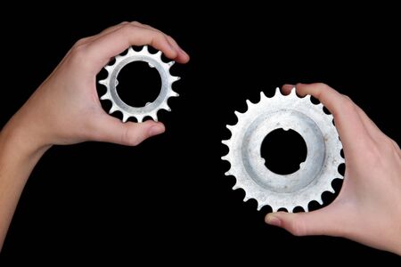 Man holding a pair of old metallic cogwheels in his hands