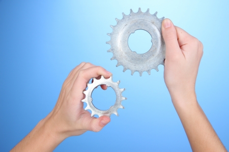 Man holding metallic cogwheels in his hands on blue backgroundの写真素材