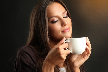 beautiful young woman with cup of coffee, on brown backgroundの写真素材