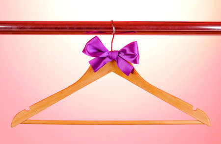 Beautiful purple bow hanging on wooden hanger on pink backgroundの写真素材
