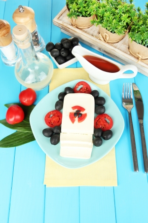 Feta cheese on plate decorated with spices and oil on blue wooden table close-upの写真素材