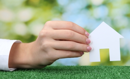 concept: woman hand with paper house on green background, close upの写真素材