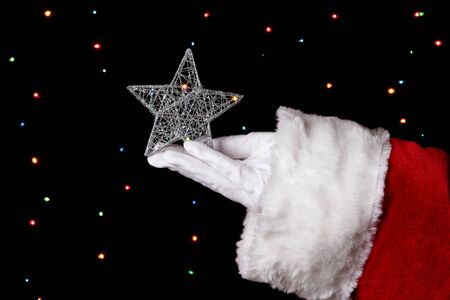 Santa Claus hand holding christmas star on bright backgroundの写真素材