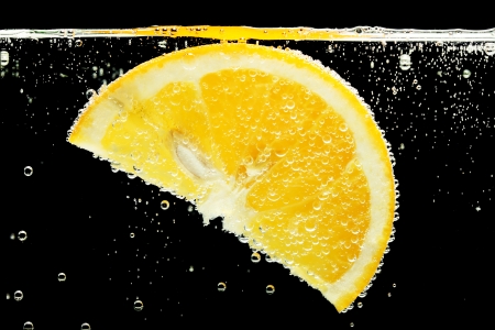 slice of orange in the water with bubbles, on black backgroundの写真素材