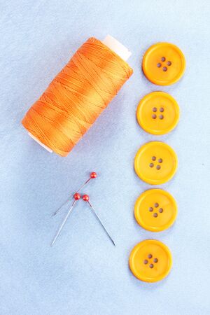 Colorful sewing buttons with thread on blue fabricの写真素材