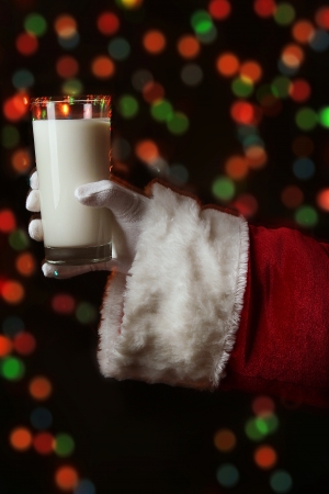 Santa Claus hand holding glass of milk on bright backgroundの写真素材