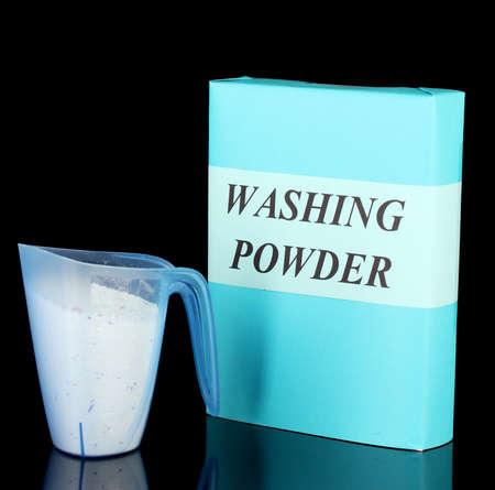 Box of washing powder with blue measuring cup, isolated on blackの写真素材