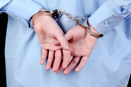 man in handcuffs on black background close-up