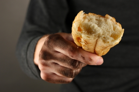 homeless man holding a white bread, close-upの写真素材