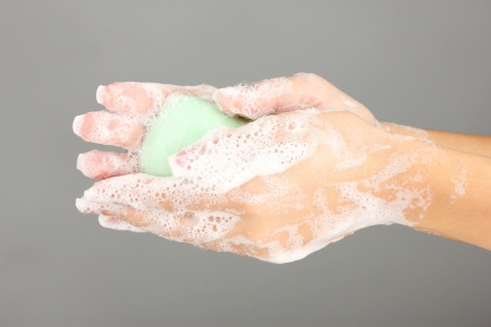 Woman's hands in soapsuds, on gray background close-upの写真素材