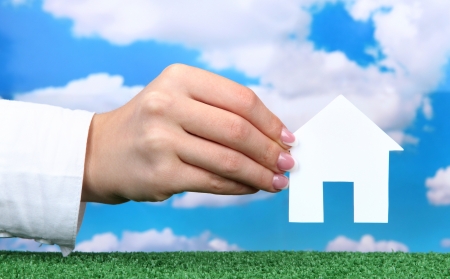 concept: woman hand with paper house on sky background, close upの写真素材