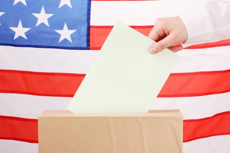 Hand with voting ballot and box on Flag of USAの写真素材