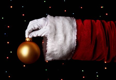 Santa Claus hand holding christmas ball on bright backgroundの写真素材