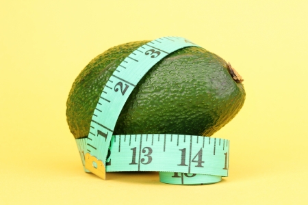 avocado with measuring tape on yellow backgroundの写真素材