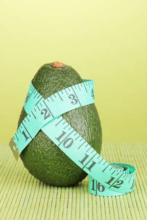 avocado with measuring tape on green backgroundの写真素材