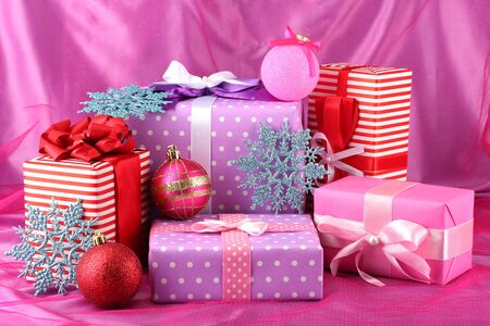 Colorful purple, red and pink gifts with Christmas balls and snowflakes on pink backgroundの写真素材