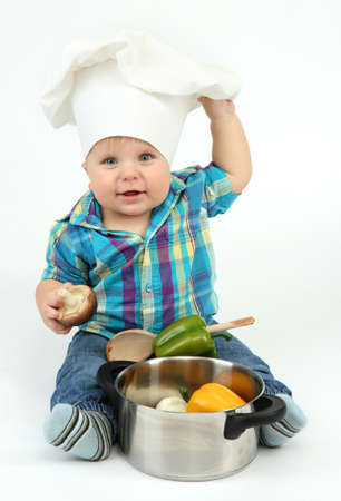Little boy in chef's hat with pan and vegetables, isolated on whiteの写真素材