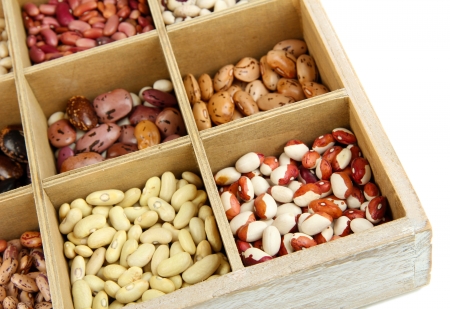 Diverse beans in wooden box sections isolated on whiteの写真素材
