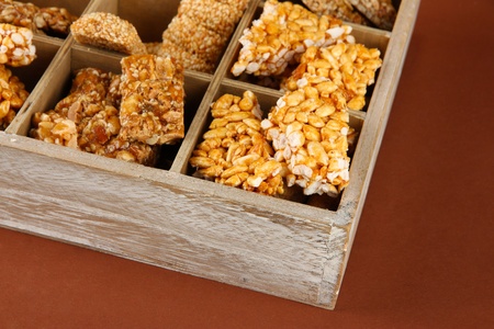 tasty sweets (kozinaki)in wooden crate on brown background