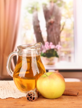 Full jug of apple juice and apple on wooden  table on bright backgroundの写真素材