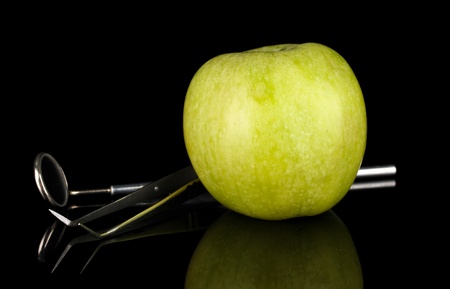 Green apple and dental tools isolated on blackの写真素材
