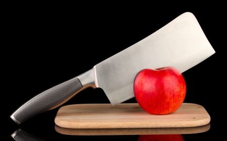 Red apple and knife on cutting board, isolated on black
