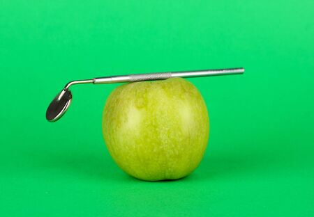 Green apple and dental tool on color backgroundの写真素材